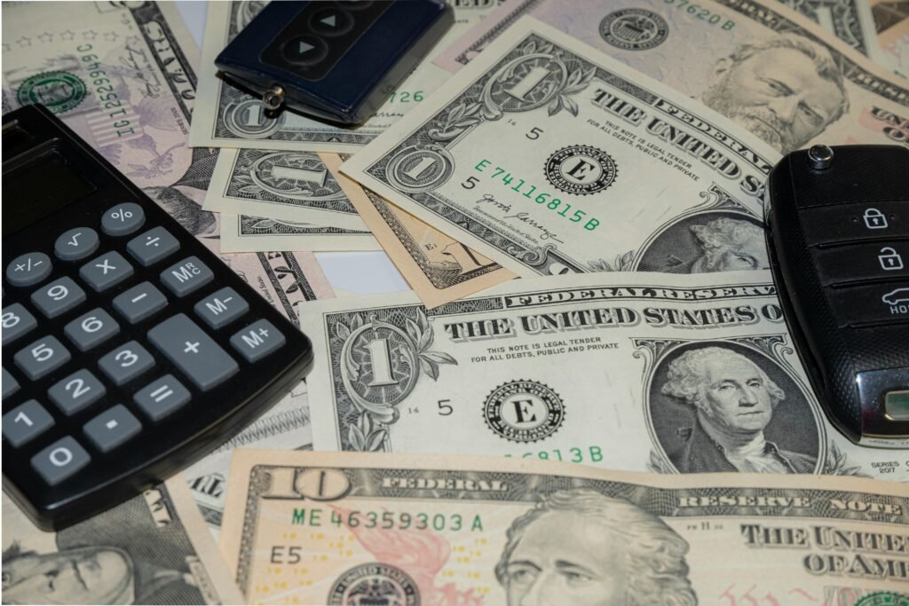 Close-up of various US banknotes, calculator, and car key illustrating finance concept